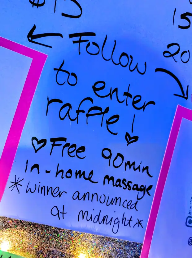 A hand-lettered board offering a free ninety minute in-home massage to a raffle winner announced at midnight