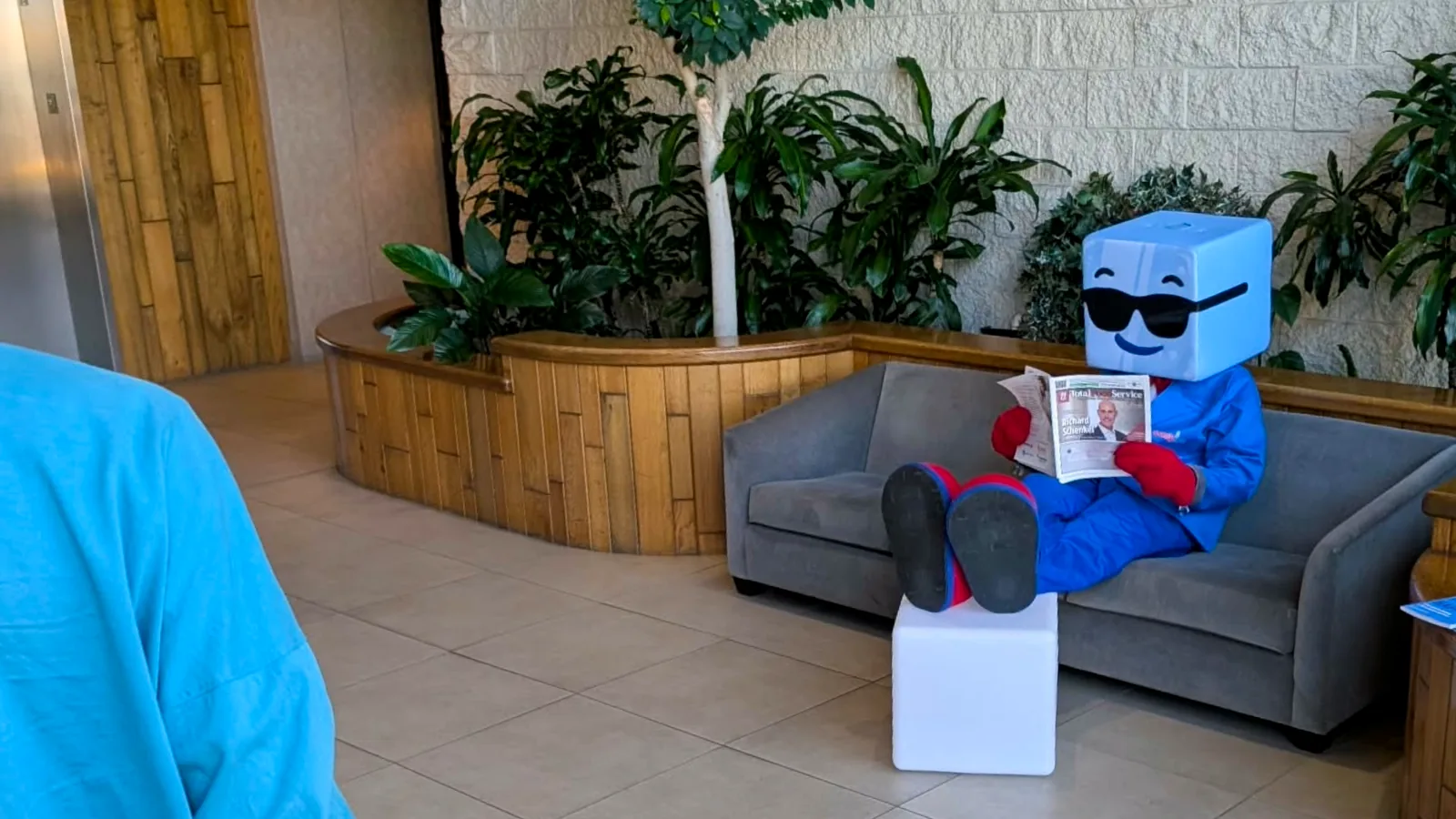 Easy Ice's blue ice-cube mascot reading a newspaper on a sofa