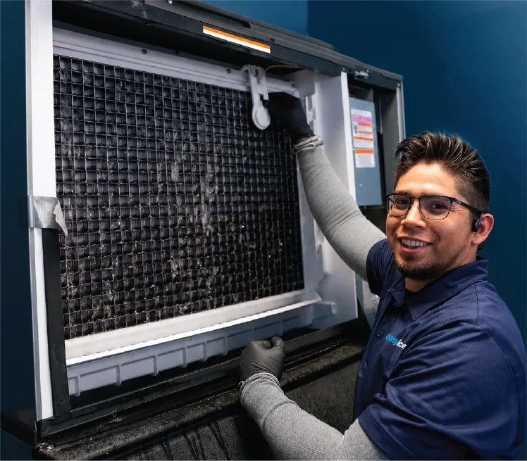 An Easy Ice technician beside the open interior of an ice machine